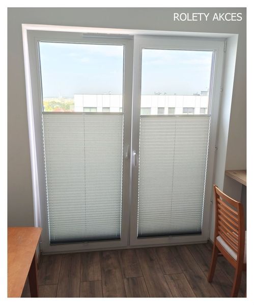 Szare plisy okienne zamontowane na drzwiach balkonowych