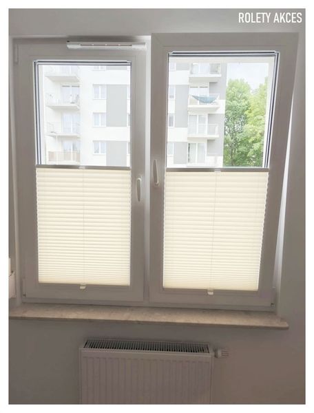 Plisy kremowe zamontowane na białych oknach z wywietrznikami